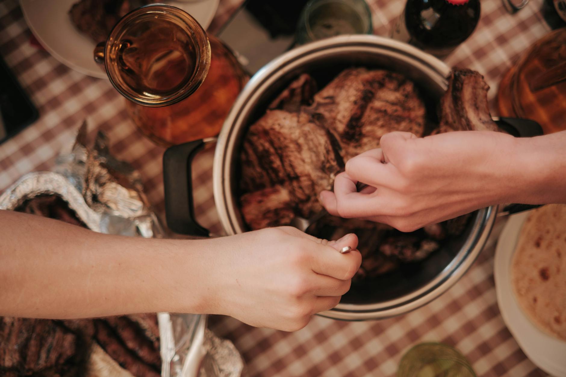 Nakładanie pieczonego mięsa z garnka na talerze przy obiedzie