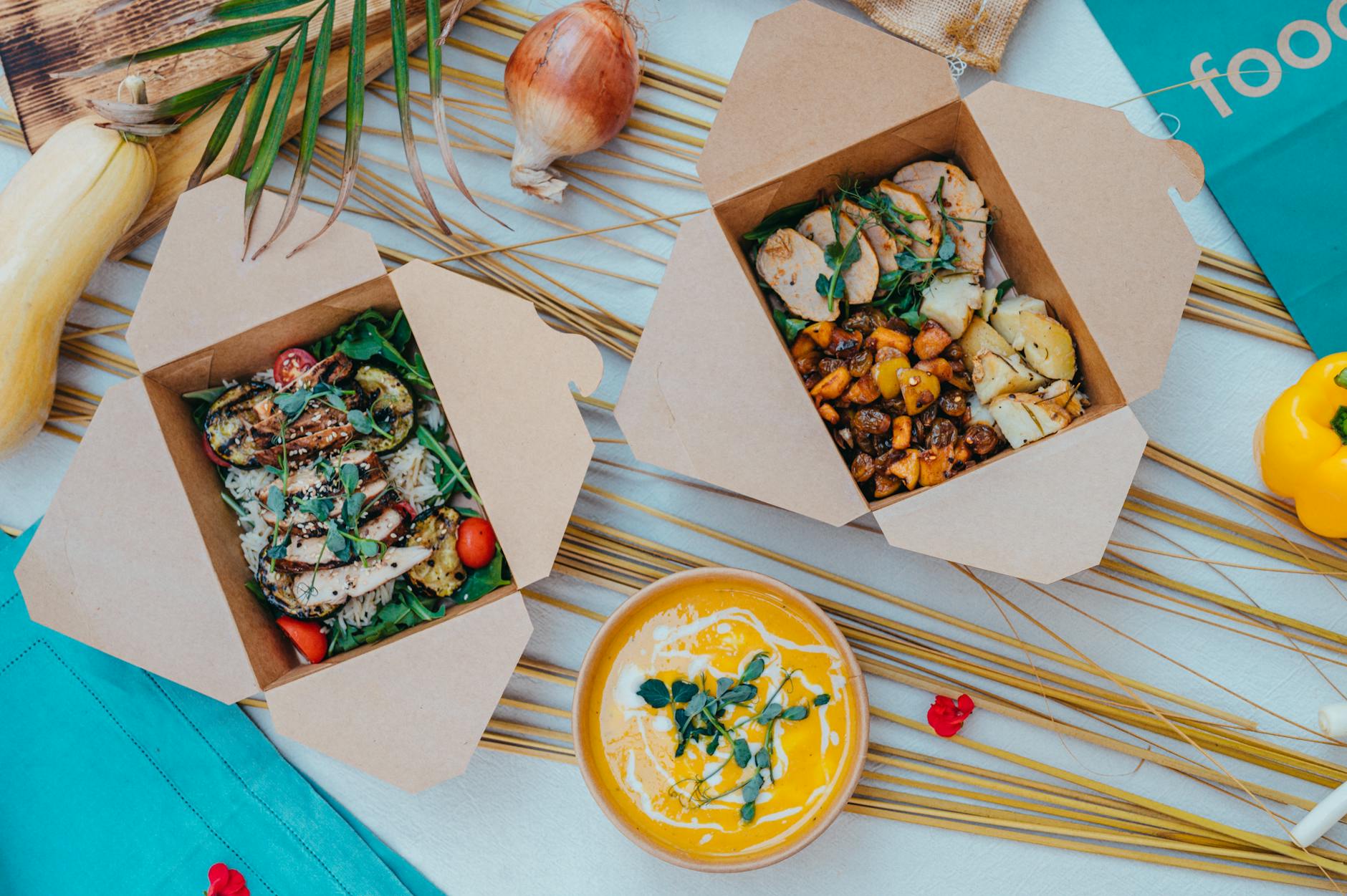 Pudełka lunchowe z kremową zupą i sałatką na kolorowym tle