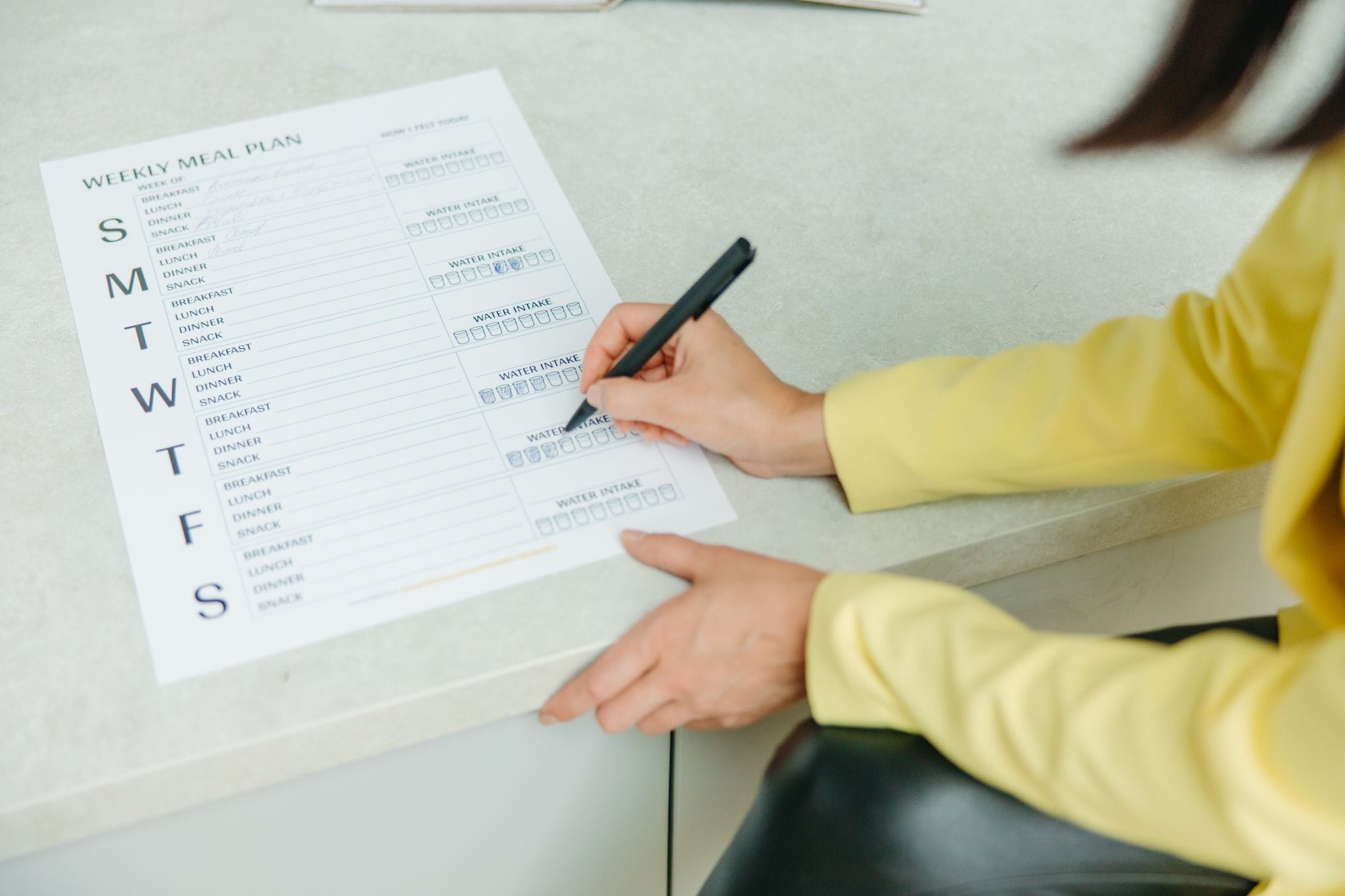 Kobieta planuje tygodniowe posiłki, wypełniając checklistę diety