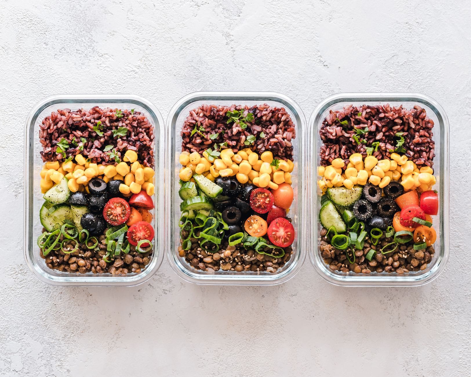 Kolorowe pudełka meal prep z kukurydzą, oliwkami, pomidorami i soczewicą