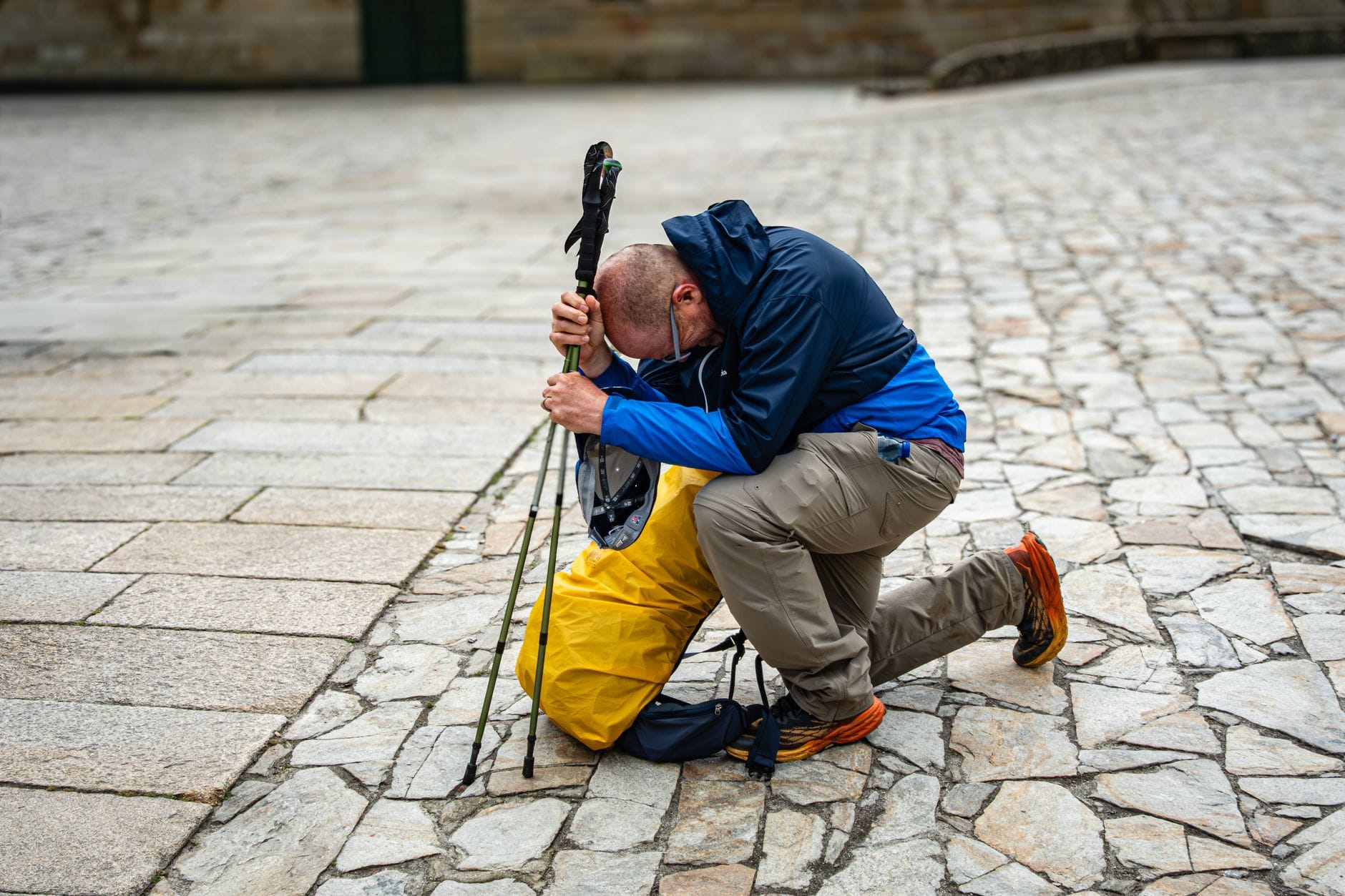 Pielgrzym odpoczywa na kamiennym bruku po zakończeniu Camino de Santiago