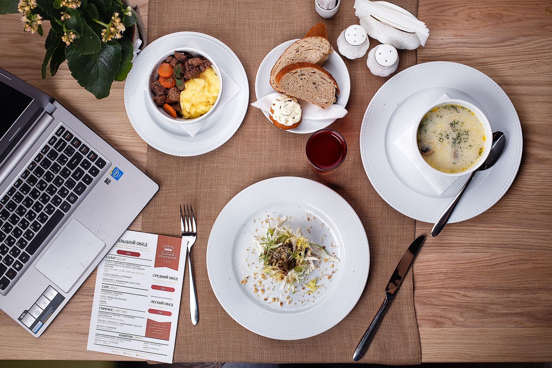 Lunch przy laptopie na domowym biurku, miska z zupą obok notatnika Lunch przy laptopie na domowym biurku, miska z zupą obok notatnika