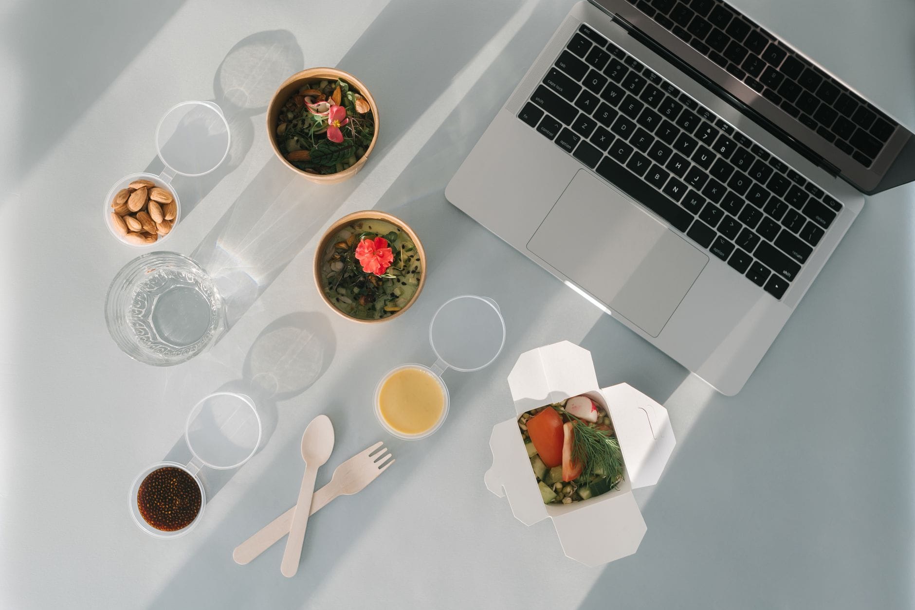 Zdrowy lunch do pracy: miski zup, migdały i laptop na biurku